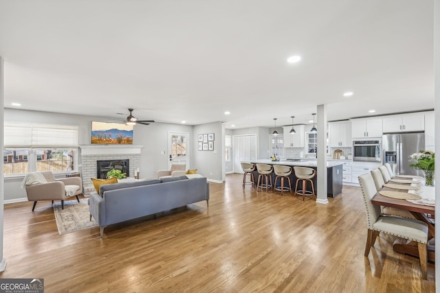 living room featuring a fireplace, light hardwood / wood-style flooring, and ceiling fan