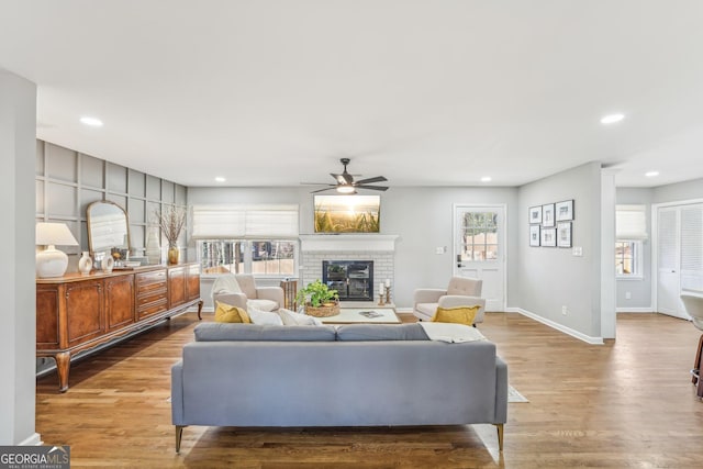 living room featuring hardwood / wood-style flooring, ceiling fan, and a fireplace