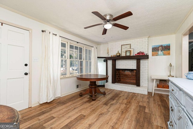 living room with ornamental molding, hardwood / wood-style floors, a fireplace, and a textured ceiling