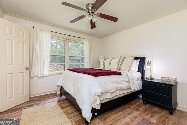 bedroom with hardwood / wood-style flooring, a textured ceiling, ceiling fan, and ornamental molding