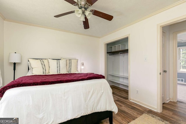 bedroom with ceiling fan, hardwood / wood-style flooring, a walk in closet, ornamental molding, and a closet