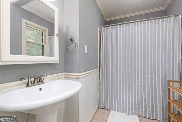 bathroom featuring crown molding, sink, a textured ceiling, and tile patterned floors