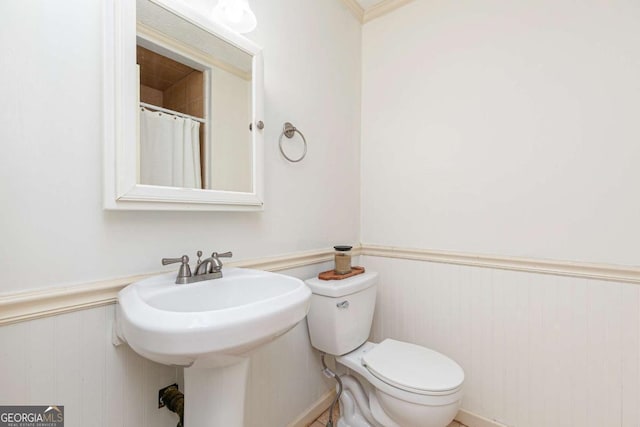 bathroom featuring toilet and wood walls