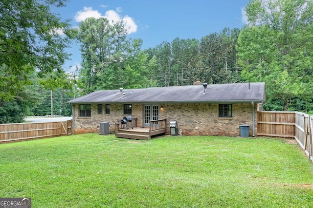 rear view of house with a deck, a lawn, and central AC