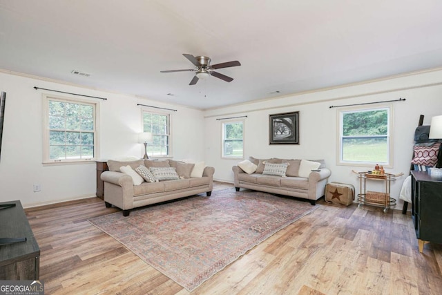 living room with crown molding, light wood-type flooring, and a wealth of natural light