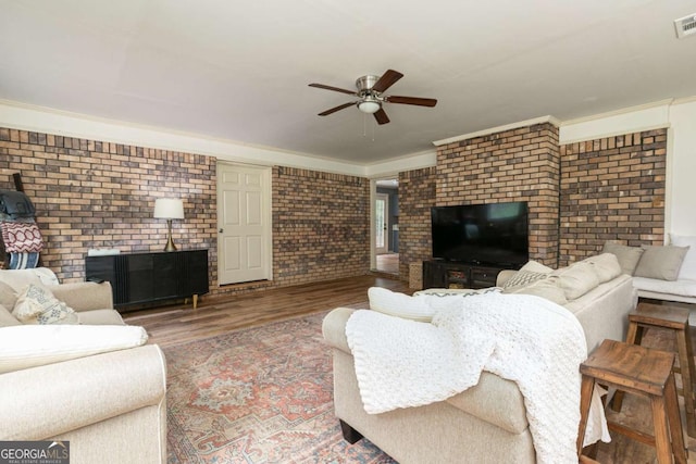 living room with ornamental molding, ceiling fan, brick wall, and hardwood / wood-style floors