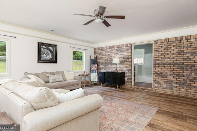 living room with crown molding, hardwood / wood-style flooring, brick wall, and ceiling fan