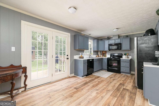 kitchen featuring a textured ceiling, black appliances, sink, ornamental molding, and light hardwood / wood-style flooring