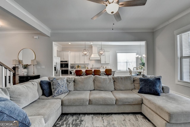 living room featuring sink, ornamental molding, and ceiling fan