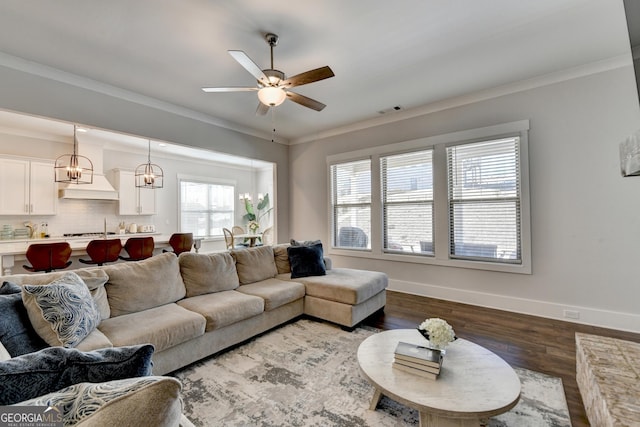 living room featuring ornamental molding, dark hardwood / wood-style floors, and ceiling fan with notable chandelier