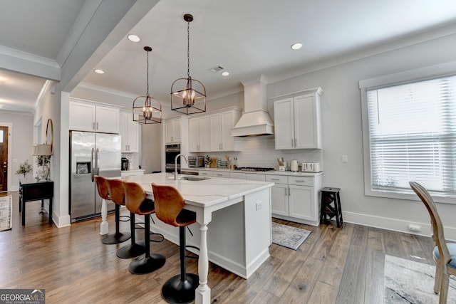 kitchen with stainless steel appliances, custom exhaust hood, an island with sink, and white cabinetry