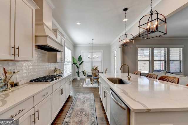 kitchen featuring pendant lighting, sink, appliances with stainless steel finishes, and a center island with sink