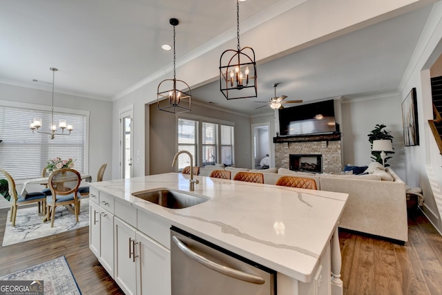 kitchen featuring decorative light fixtures, dishwasher, sink, white cabinets, and a center island with sink