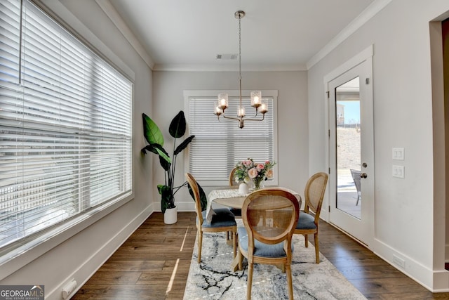 dining space featuring crown molding, dark hardwood / wood-style flooring, a chandelier, and a wealth of natural light