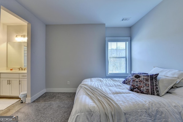 carpeted bedroom with ensuite bathroom and sink