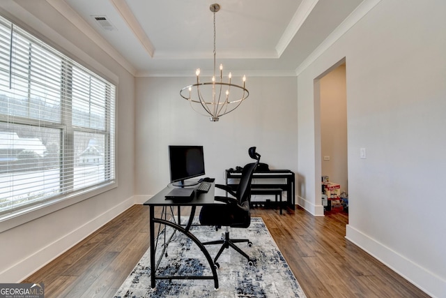 home office with a raised ceiling, dark wood-type flooring, and an inviting chandelier