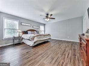 bedroom featuring ceiling fan, multiple windows, and dark hardwood / wood-style floors