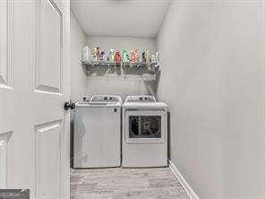 laundry area with light wood-type flooring and washer and clothes dryer