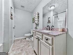 bathroom featuring a textured ceiling, toilet, and vanity