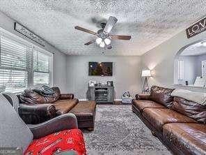 living room with ceiling fan and a textured ceiling