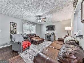 living room with ceiling fan, a textured ceiling, and hardwood / wood-style flooring