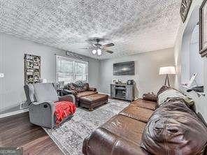 living room featuring ceiling fan, hardwood / wood-style floors, and a textured ceiling