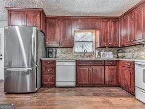 kitchen featuring stainless steel fridge, white dishwasher, sink, hardwood / wood-style floors, and range