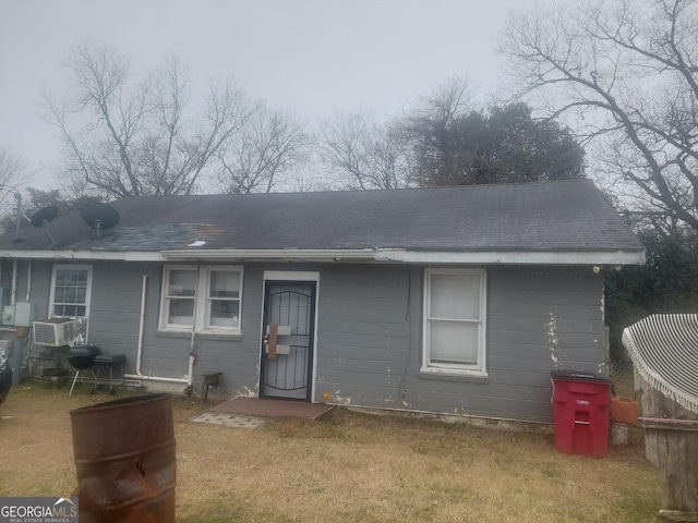 rear view of property featuring cooling unit and a yard