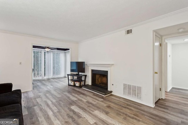 living area featuring visible vents, ornamental molding, and wood finished floors