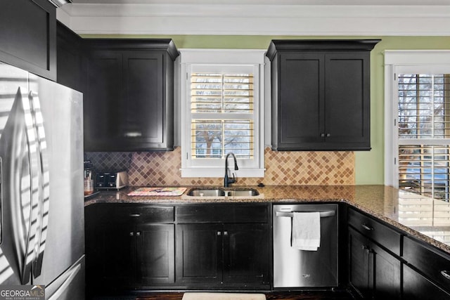 kitchen with decorative backsplash, sink, dark stone countertops, ornamental molding, and stainless steel appliances