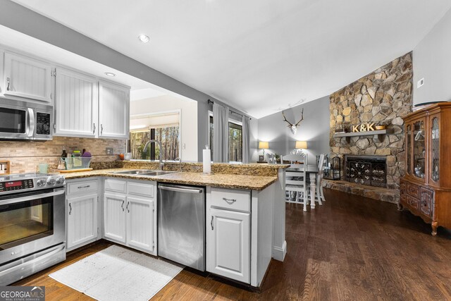 kitchen with a fireplace, white cabinetry, sink, kitchen peninsula, and stainless steel appliances