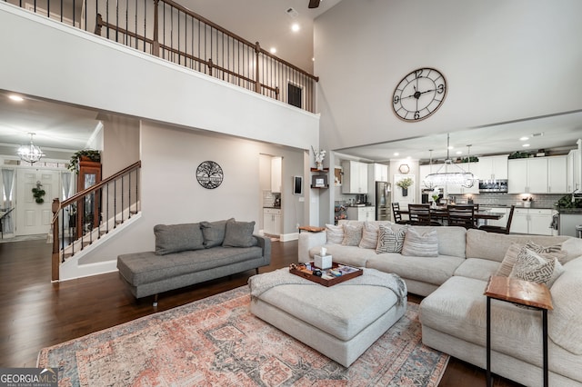 living room featuring an inviting chandelier, dark hardwood / wood-style flooring, and a high ceiling