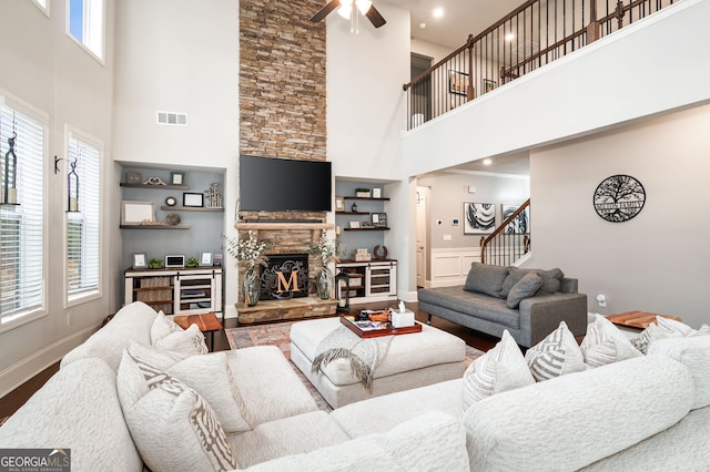 living room with hardwood / wood-style flooring, a stone fireplace, and ceiling fan