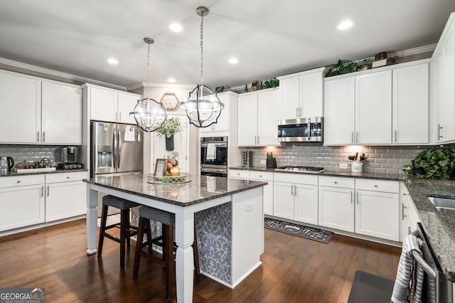 kitchen featuring appliances with stainless steel finishes, pendant lighting, white cabinets, and dark stone counters