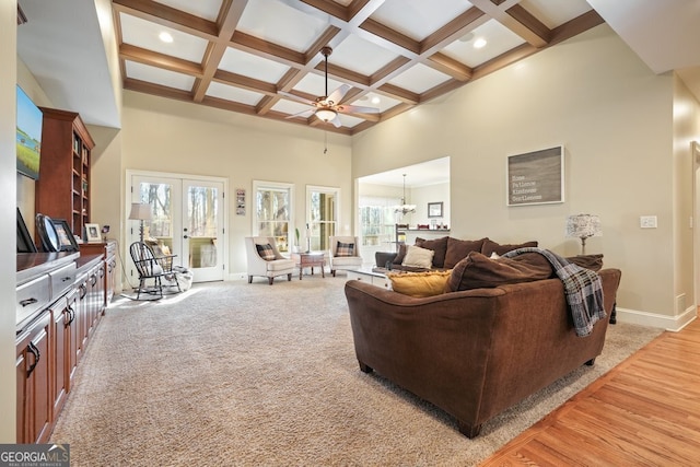 carpeted living room with a towering ceiling, beamed ceiling, coffered ceiling, french doors, and ceiling fan