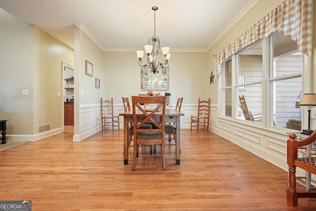 dining space with light hardwood / wood-style floors, a notable chandelier, and ornamental molding