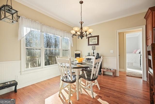 dining room with hardwood / wood-style flooring, an inviting chandelier, and ornamental molding