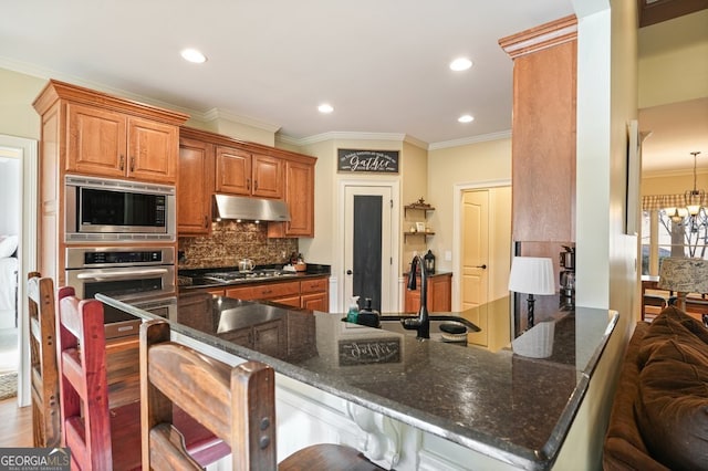 kitchen featuring a notable chandelier, stainless steel appliances, kitchen peninsula, and a breakfast bar area