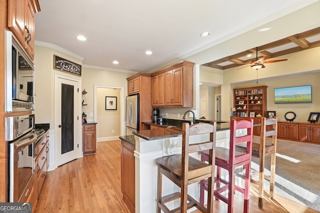 kitchen with appliances with stainless steel finishes, coffered ceiling, beam ceiling, kitchen peninsula, and dark stone counters