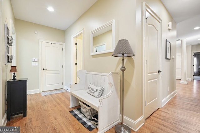 hallway featuring decorative columns and light wood-type flooring