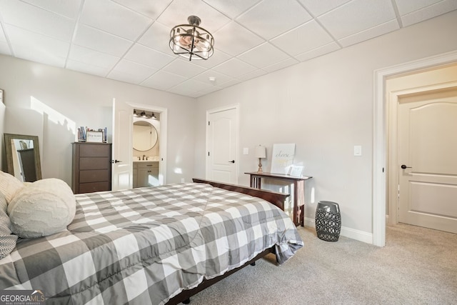 carpeted bedroom featuring a drop ceiling and ensuite bathroom