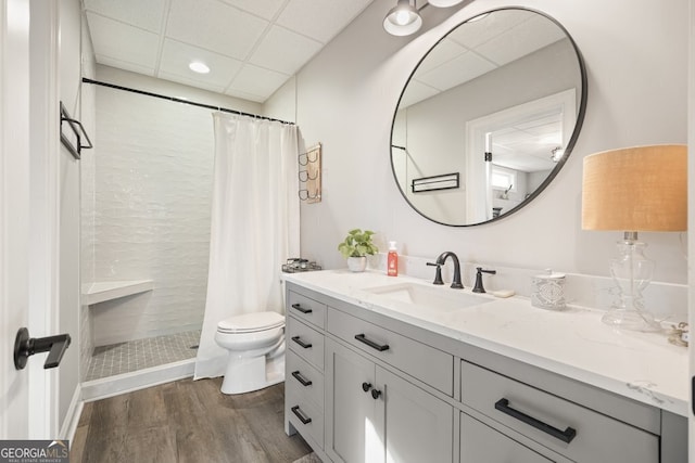 bathroom featuring toilet, wood-type flooring, a drop ceiling, a shower with shower curtain, and vanity