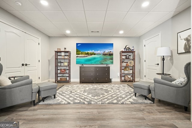 living room featuring hardwood / wood-style flooring and a drop ceiling