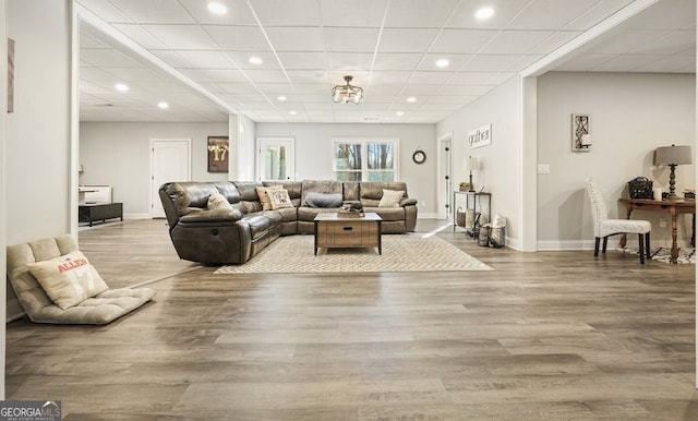 living room featuring a paneled ceiling and light hardwood / wood-style flooring