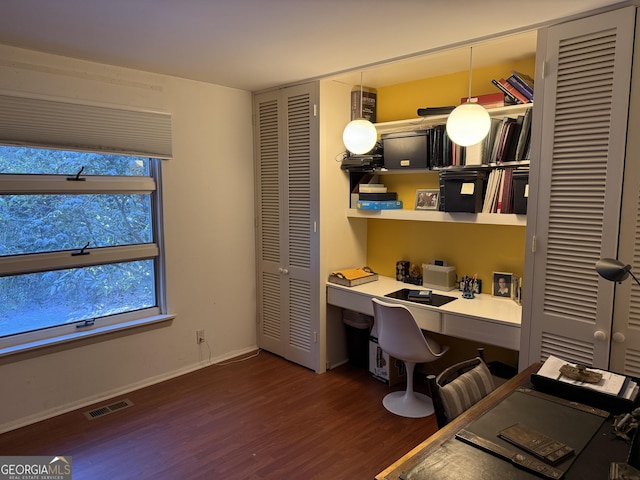 home office with built in desk and dark hardwood / wood-style floors