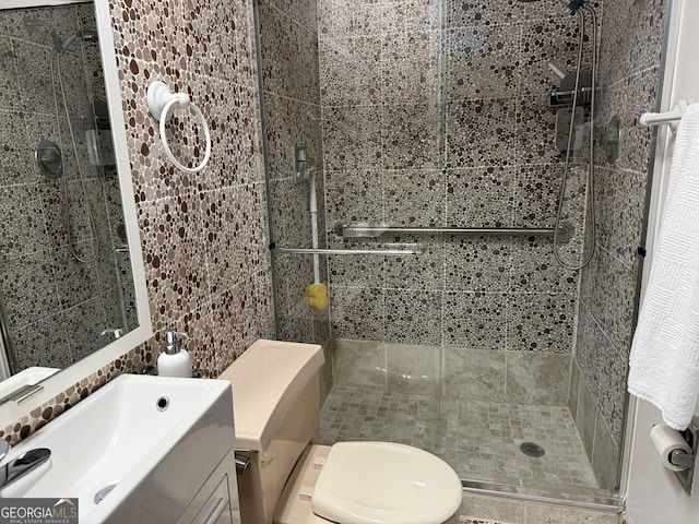 bathroom featuring vanity, toilet, tile walls, and walk in shower