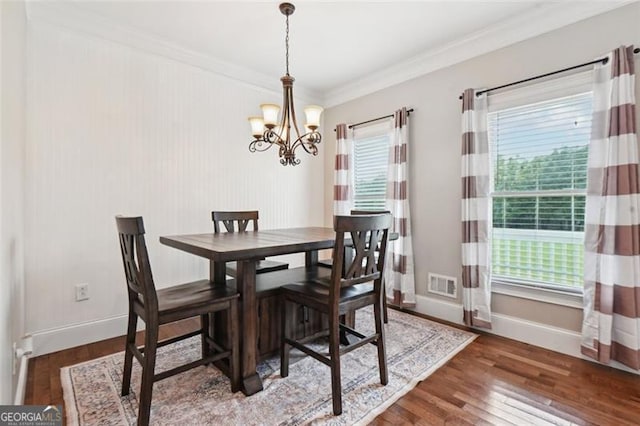 dining space featuring an inviting chandelier, ornamental molding, and dark hardwood / wood-style floors