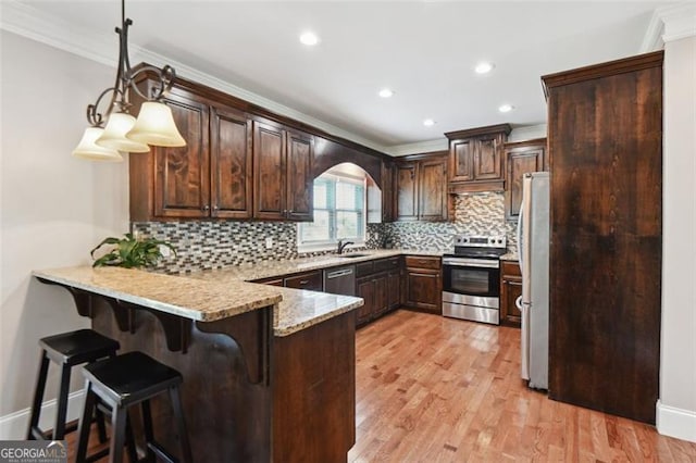 kitchen featuring ornamental molding, stainless steel appliances, kitchen peninsula, and hanging light fixtures