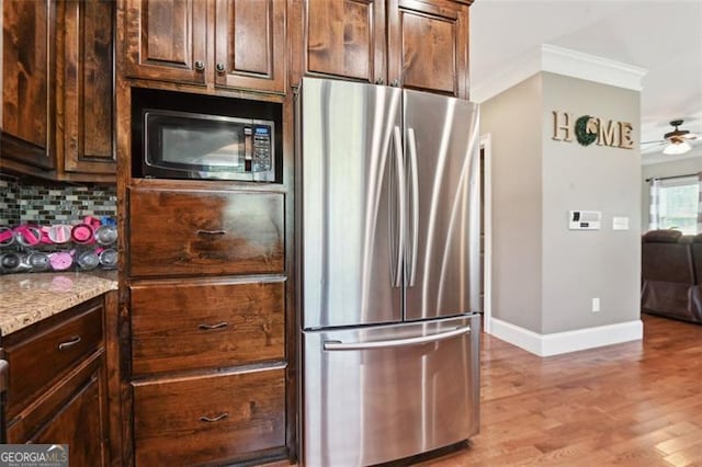 kitchen with tasteful backsplash, dark brown cabinetry, stainless steel appliances, crown molding, and light stone countertops