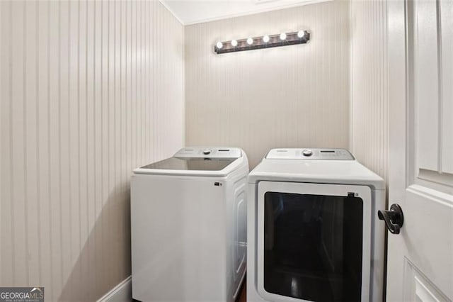 laundry room featuring washer and clothes dryer and wood walls